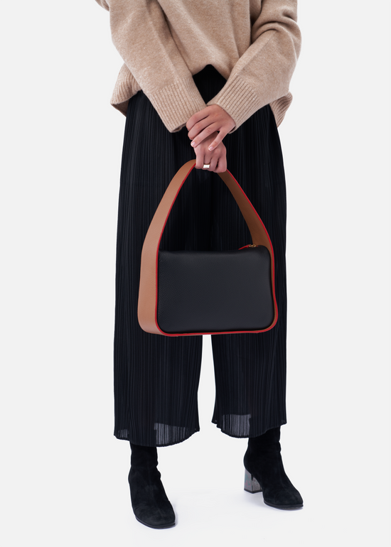 Grete pebble leather shoulder bag in black / caramel with red edge paint