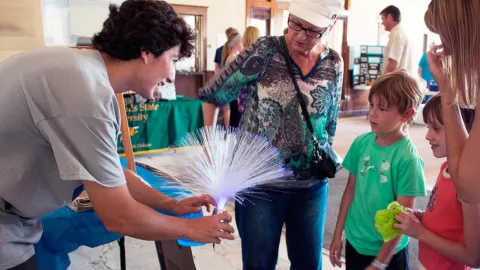 man shows a science exhibit to children