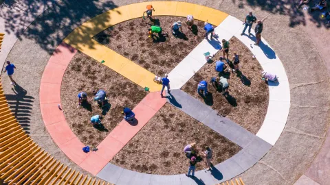 A photo of Čhaŋgléška Wakȟáŋ from above showing the medicine wheel and a number of poeple in the garden enjoying planting