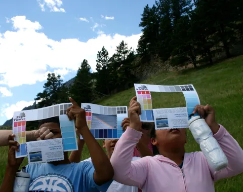 Students identifying clouds by look up at the sky through the rectangular hole in the paper cloud viewer.