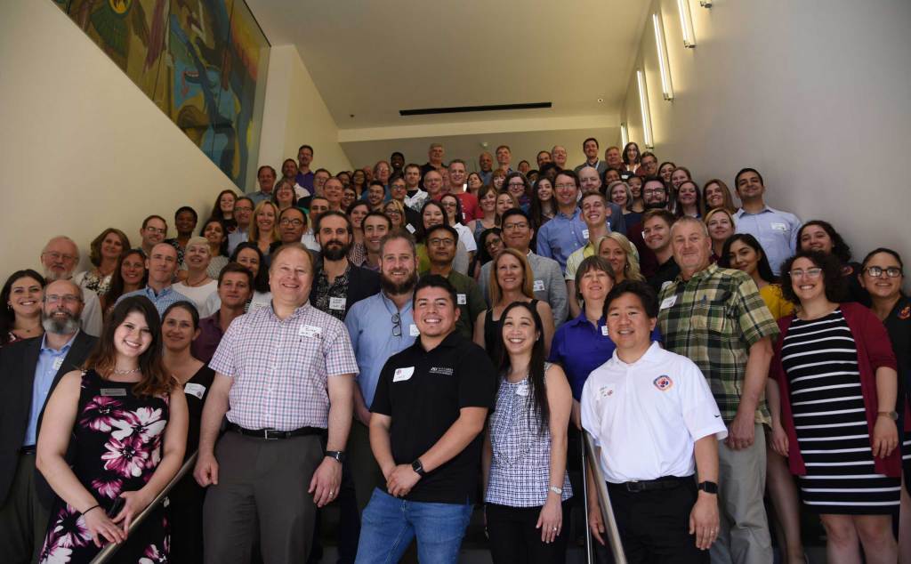 A large group of people standings together on stairs for a photo.