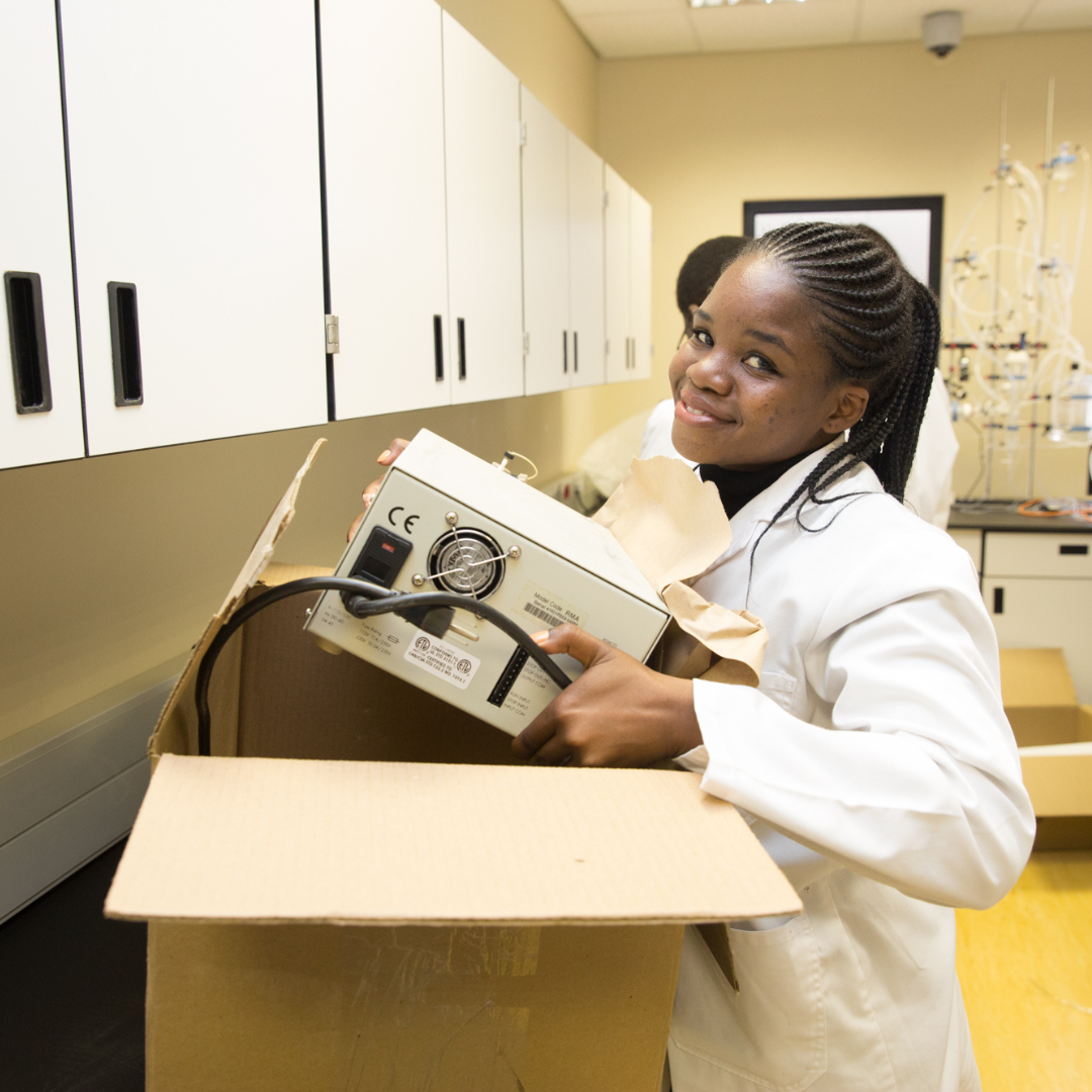 A scientific researcher carrying equipment and smiling to the camera