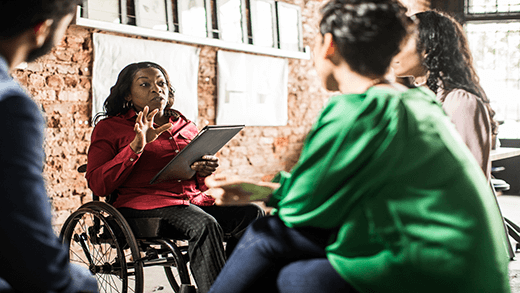 Businesswoman in wheelchair leading group discussion in creative office