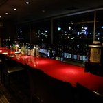 Dining Bar Suito - 大橋川の夜景を望むカウンター．窓下に大量のアルコール類が．