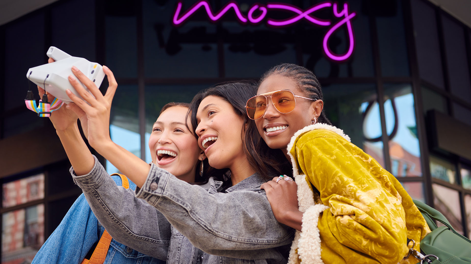 friends taking a selfie in front of a moxy hotel