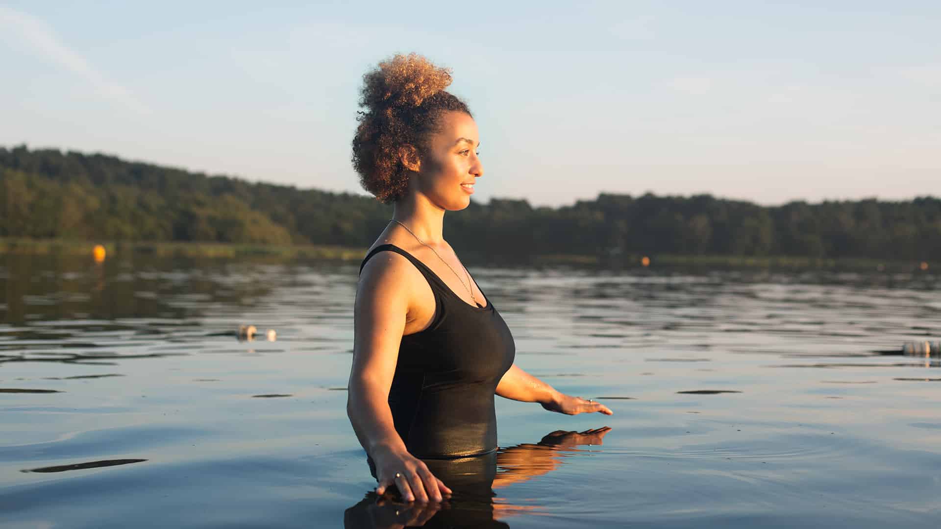 woman standing in a lake during sunset