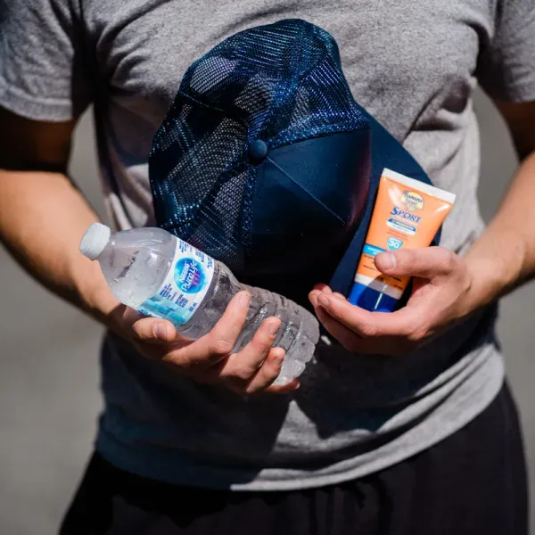 Community member holding water, sunscreen and hat