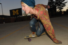 A student zips down the slope of the empty parking lot on the north side of Michigan Stadium as the last minutes of daylight begin to fade.