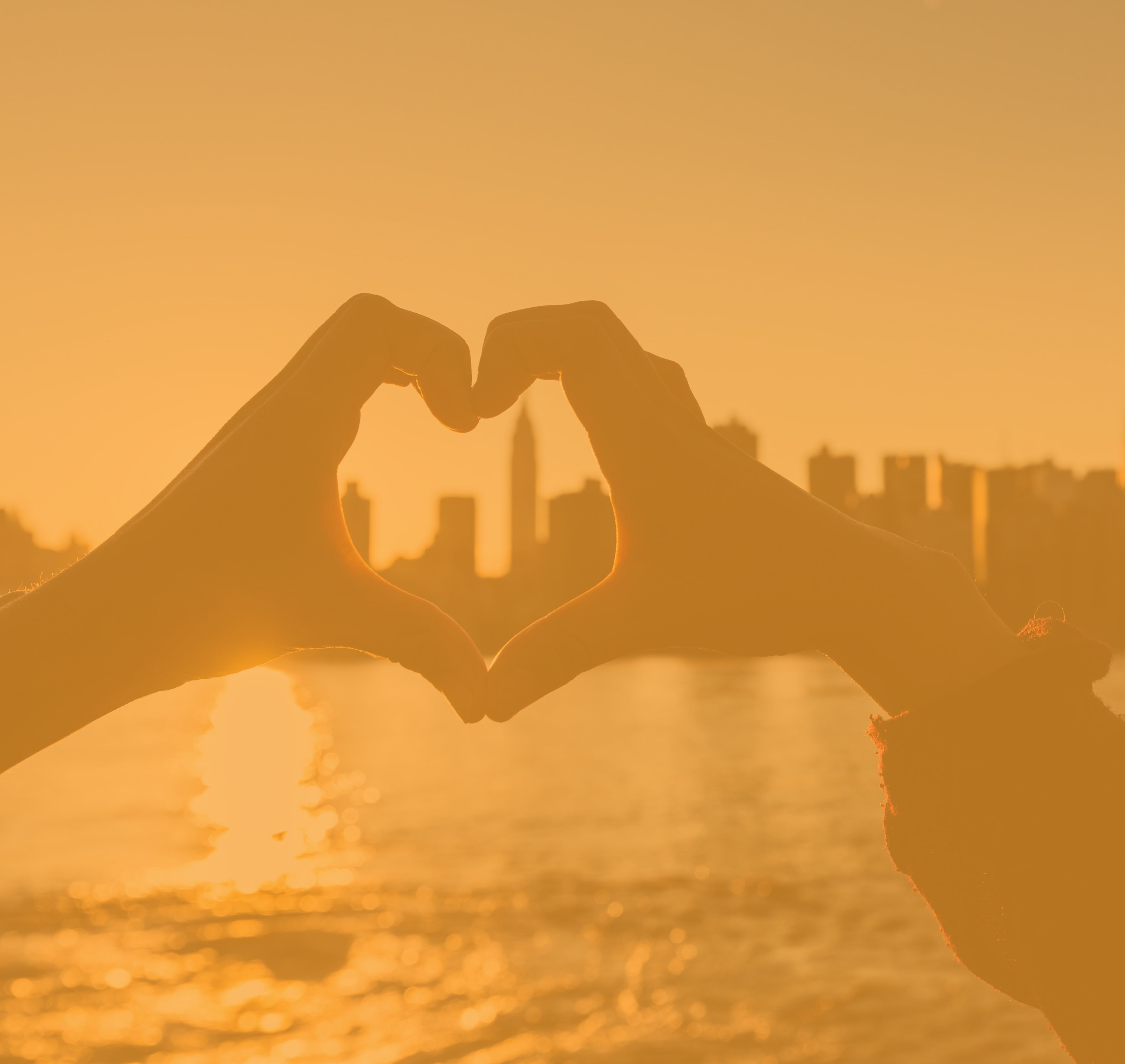 Hands forming a heart around a skyline