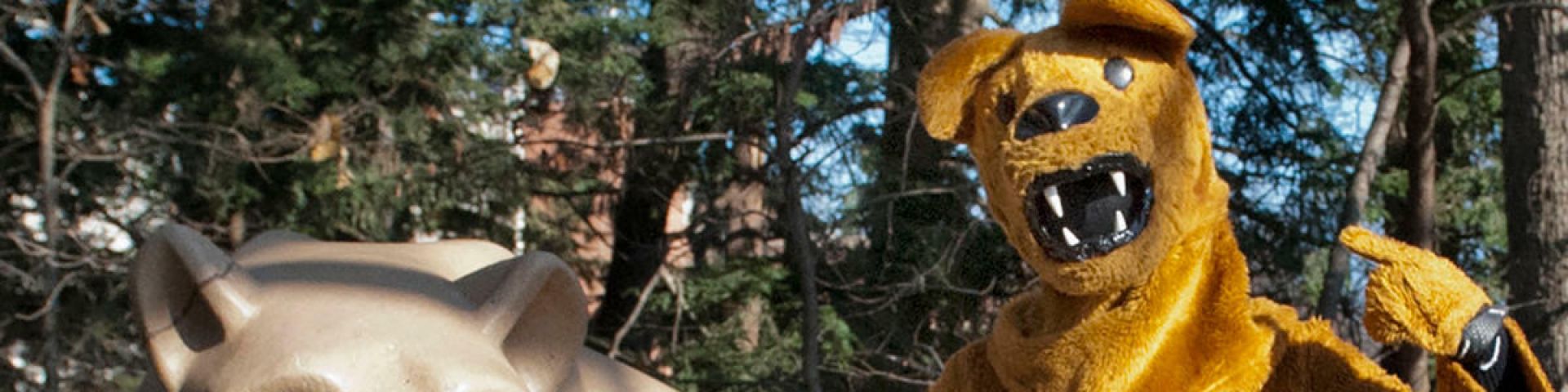 Nittany Lion mascot posing with Lion Shrine statue.