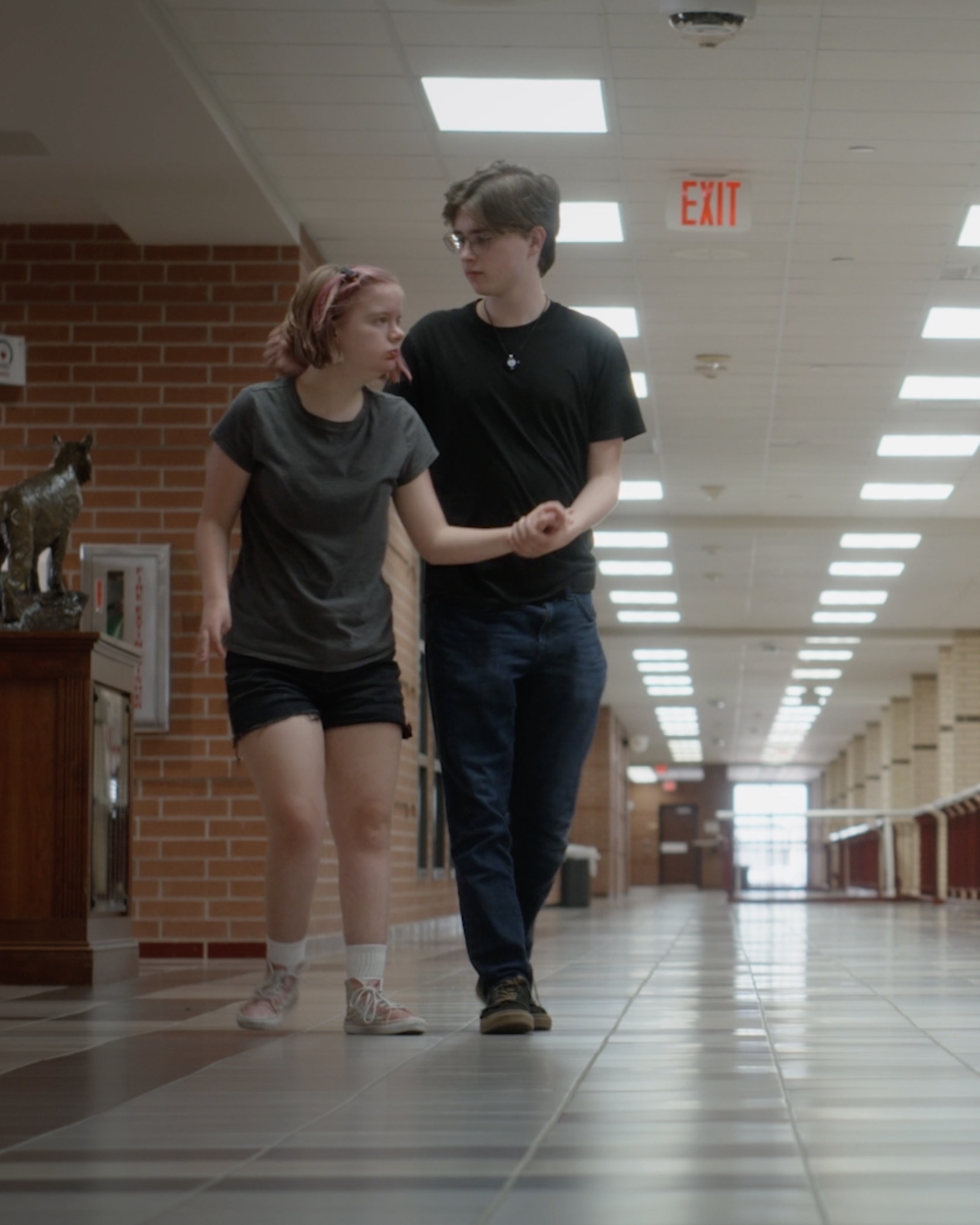 Two people walking down a hallway.