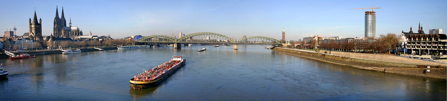 Sicht op de Ryn yn Keulen fan de Deutzer Brücke ôf. Alhiel lofts yn de fierte de tv-toer, dan de tsjerke Groß St. Martin en de Dom, it blauwe dak fan it musicalgebou, de brêge Hohenzollernbrücke, oan de oare kant de Ryn de toer fan de Messe, en uterst rjochts de Kölnturm (doe noch yn oanbou).