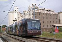 Tram departing Lewisham West light rail station showing the Mungo Scott flour mill in the background