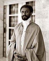 Portrait noir et blanc en buste d'un homme barbu portant un manteau bouffant par dessus une tunique blanche