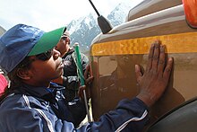 Indian woman touches a large brown vehicle