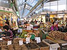 Vendors sell root vegetables at Gyeongdong Market, a crowded indoor mall with a glass roof