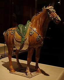 fotografie sošky koně, kůň hnědý, sedlo zelené na béžových pokrývkách, pečlivě vypracované detaily koně, sedla a ozdobného řemení