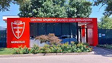 The front entrance gate of AC Monza's Centro sportivo Silvio e Luigi Berlusconi – Monzello, with trees in the background