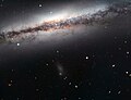 Aufnahme mithilfe des Very Large Telescope. Unter­halb der Bild­mitte is eine diffuse Satelliten­galaxie als bläu­liche Wolke zu erkennen.[5]