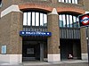 A brown-bricked building with a rectangular, dark blue sign reading "PIMLICO STATION" in white letters and a black sign reading "UNDERGROUND"