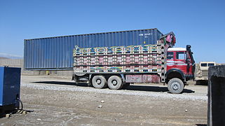 Un porteur transportant un conteneur qui est visiblement un chargement non approprié aux capacités du véhicule, trop lourd, trop volumineux et par conséquent dangereux (Afghanistan).