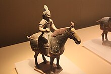 fotografie keramické figurky muže na koni, figurka stojí na stole, muž je v brnění, převládající barva je béžová, na obou jsou však zbytky původních barev, například načervenalé hřívy koně
