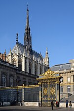 Foto des schlanken, hohen Sakralbaus von Osten auf Apsis und Nordfassade. Der untere Teil der Kapelle ist vor der Kamera verdeckt durch das davorstehendes Gebäude des Palais de Justice. Sichtbar sind die obere Hälfte der hohen Glasfenster und das Dach mit hohem Dachreiter.