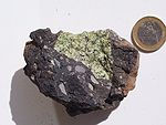Ksenolit peridotita iz plašča (zelen) v temni vulkanski bombi (Eifel, Nemčija)