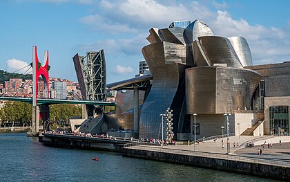 Guggenheimovo muzeum v baskickém Bilbau podle návrhu architekta Gehryho, vpředu s Kapoorovou sochou Vysoký strom a oko z koulí a zavěšeným mostem la Salve přes Nervión