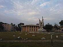 University buildings, with statue and scattered rocks