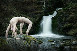 Fotografia de acrobacia artística, próxima a uma cachoeira, na Escócia.