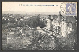 Photographie en noir et blanc d'un bâtiment imposant et d'un village en contrebas.