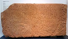 Die nur schwer leserliche Inschrift auf einem Stein lautet: „Hariulfus protector / domesticus, filius Hanhavaldi, regalis gentis Burgundionum qui / vixit annos XX et menses nove(m) et dies nove(m) / Reutilo avunculus ipsius fecit“
