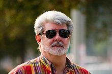 Homme avec une barbe et des cheveux blancs qui porte des lunettes de soleil.
