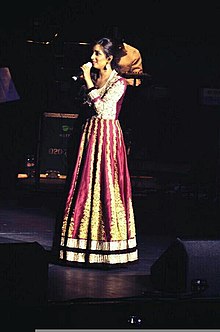 A woman singing on the stage wearing a red dress