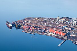 Foto einer Landspitze, an deren Küstenlinie sich en Hafen befindet