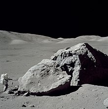 Un astronaute à proximité d'un important massif rocheux.