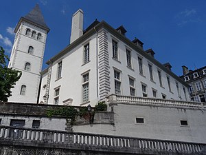 Photographie en couleurs d'un bâtiment à étages avec un beffroi à l'un de ses angles.