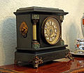 Un orologio da caminetto nero di Seth Thomas, tipico stile americano della fine del XIX secolo. La "serpentina" e la "pietra" dei pilastri sono realizzate in celluloide incollata su legno.
