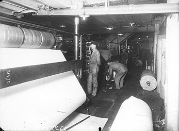 Photographie en noir et blanc d'ouvriers travaillant à la création d'un journal papier au début du XXe siècle.