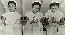 Three young, smiling Chinese women drying dishes