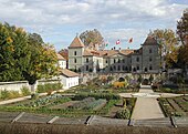 Photographie en couleur d'un château et de son jardin.