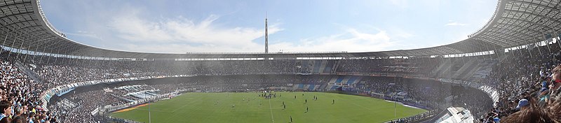 Panorâmica do estádio Presidente Juan Domingo Perón lotado de torcedores do Racing. Combine com o público visitante.