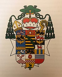 Arcibiskupské galero ve znaku Mořice Adolfa Saského, po papežské instrukci v roce 1969 již ve znaku nejsou užívány mitra a berla (v tomto případě je zde navíc ještě knížecí koruna)