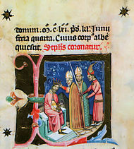 A bishop puts a crown on the head of a man sitting on the throne