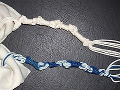 Dos tzitzit, uno blanco y otro con hebras azules.