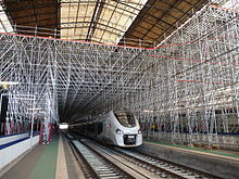 Train passant sous un échafaudage métallique.