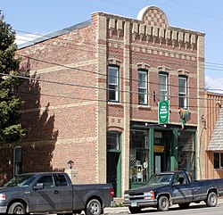 A small, two-story brick building directly fronting a street with parked trucks