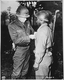 Patton accroche une médaille sur la veste d'un soldat afro-américain dont le fusil est en bandoulière.