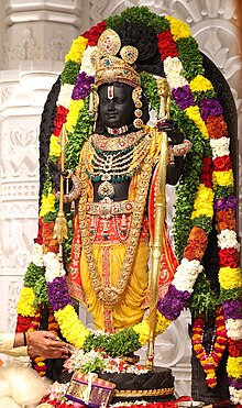 An image of an idol resembling a 5-year-old child Rama, wearing a crown, dressed as a prince, and adorned with ornaments. The idol is sculpted from a black granite stone known locally as Krishna Sila and is 51 inches tall. The deity holds a bow and an arrow as weapons.